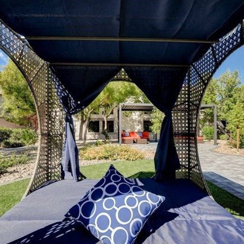 A canopy bed with a blue pillow and a canopy with a pattern on it.