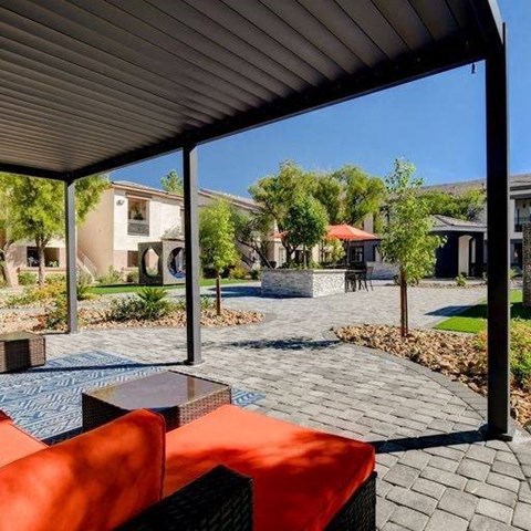 A patio with a table and chairs is covered by a roof.