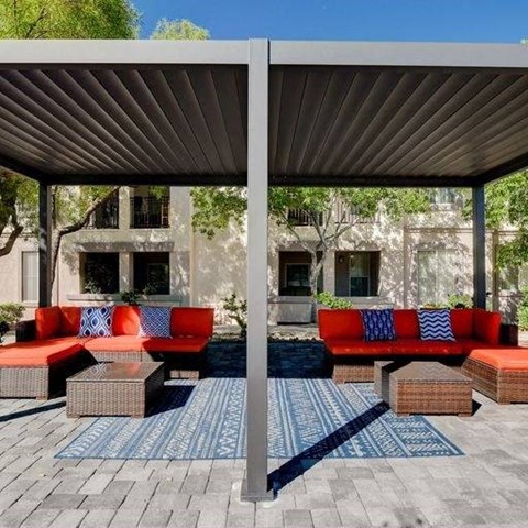 A patio with a red couch and a blue rug.