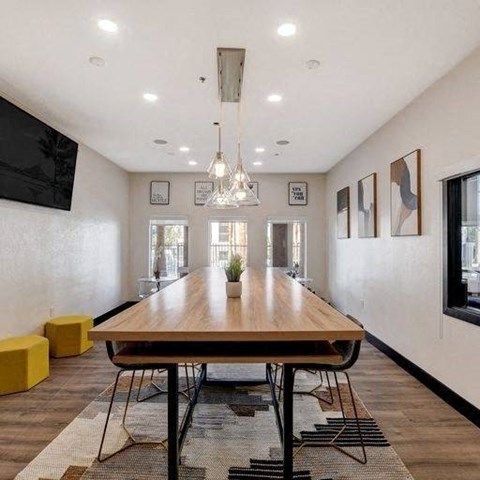 A modern dining room with a long wooden table and yellow stools.