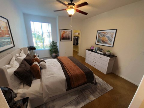 A bedroom with a bed, a ceiling fan, and a window.