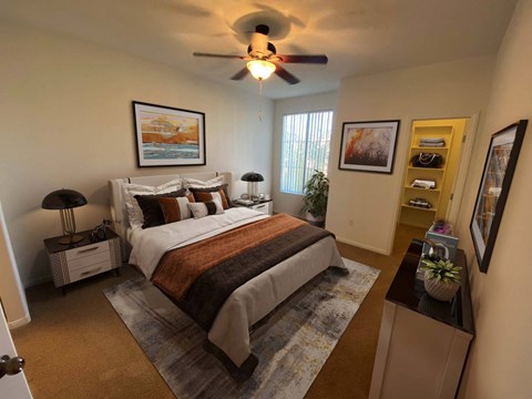 A bedroom with a bed, nightstands, and a ceiling fan.