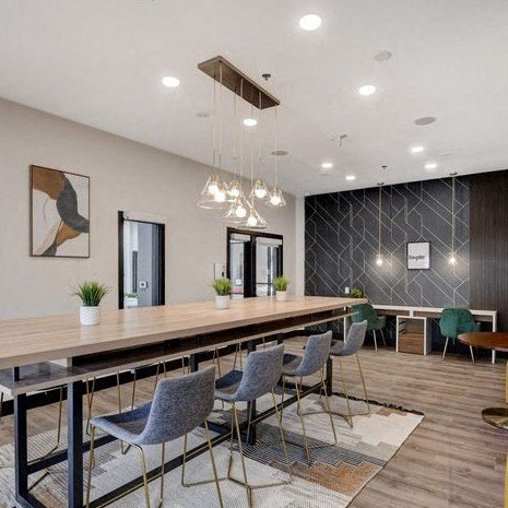 A modern dining room with a long table and grey chairs.