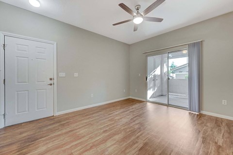 A room with a ceiling fan and sliding glass doors.