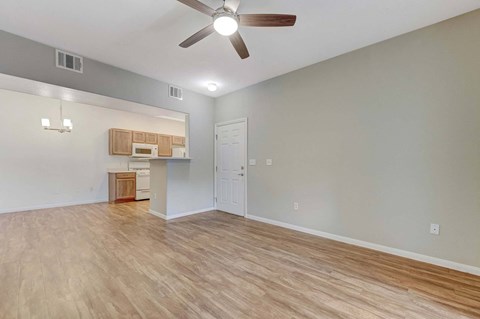 A room with a ceiling fan and light fixture, a small kitchenette, and a door.