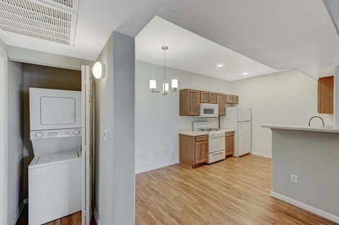 A kitchen with white appliances and wooden floors.