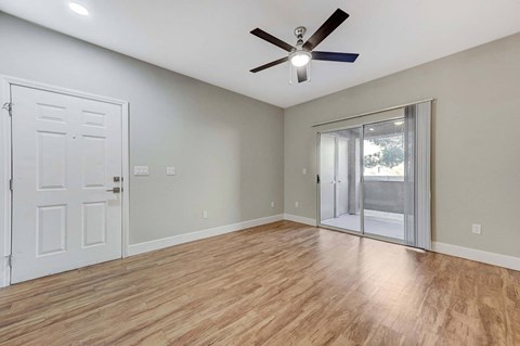 A room with a ceiling fan and wooden flooring.