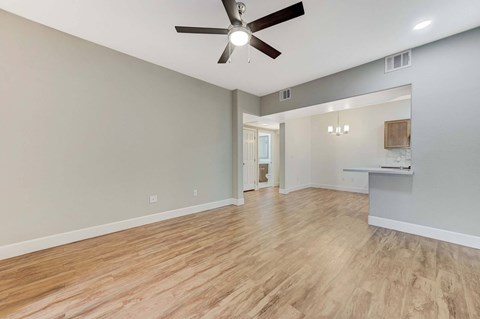 A room with a ceiling fan and wooden flooring.