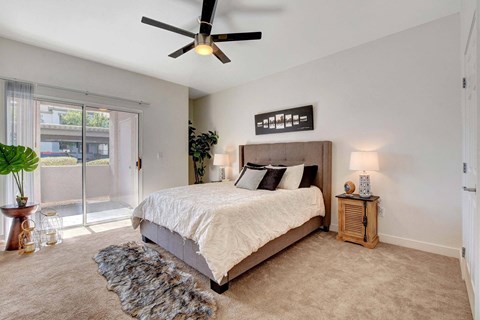 A bedroom with a large bed and a ceiling fan.