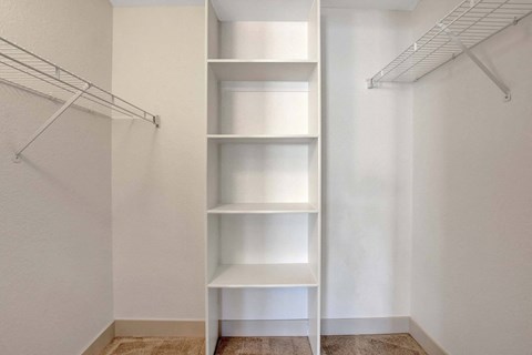 A white closet with shelves and a clothes hanger.