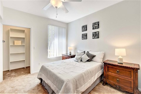 A bedroom with a bed, dresser, and a ceiling fan.