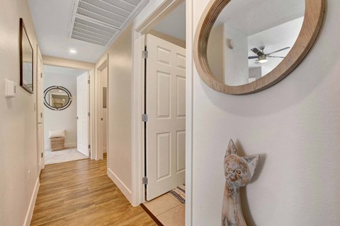 A hallway with a round mirror and a wooden floor.