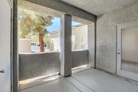 A room with a sliding glass door leading to a patio with a tree.