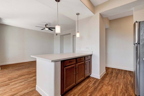 A kitchen with wooden floors and a white island with brown cabinets.