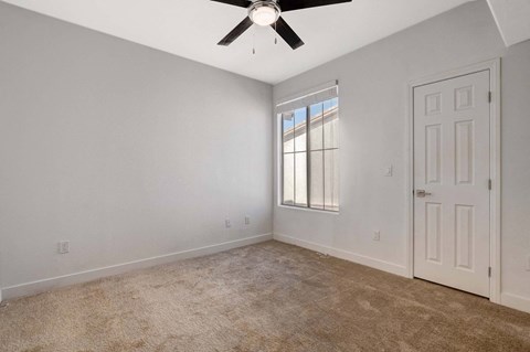 A room with a ceiling fan and a window with blinds.