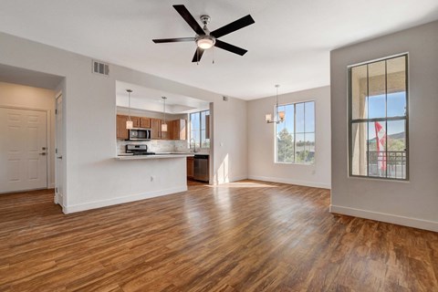 A spacious living room with a ceiling fan and hardwood floors.