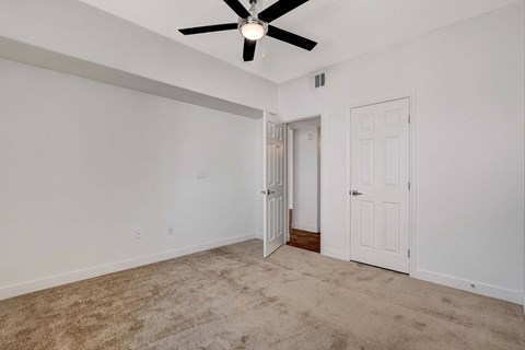 A room with a ceiling fan and carpeted floor.