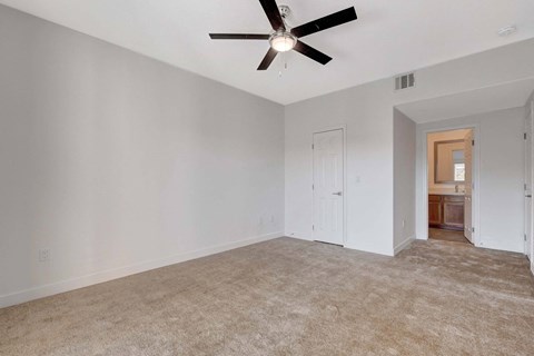 A room with a ceiling fan and carpeted floor.