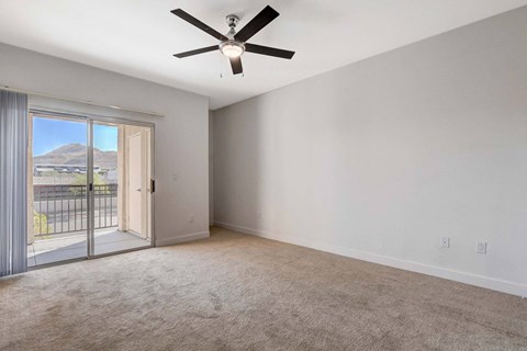 A room with a ceiling fan and sliding glass doors.