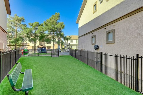 A small green park with a bench and a fence.