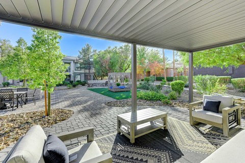 A patio with a couch, chairs, and a table with a pillow on it.