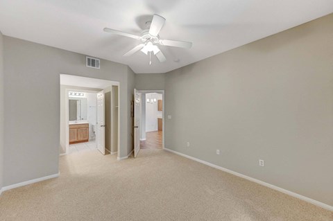 A room with a ceiling fan and carpeted floor.