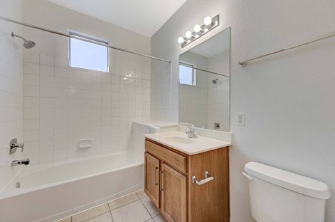 A white bathroom with a wooden cabinet and a white tub.