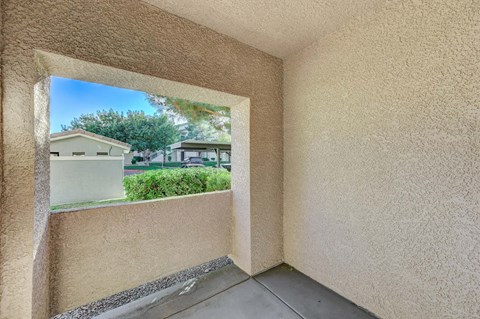 A view of a house through a window in a room with beige walls.