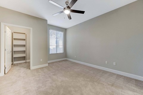 A room with a ceiling fan and a window with blinds.