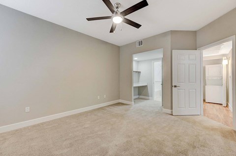 A room with a ceiling fan and carpeted floor.