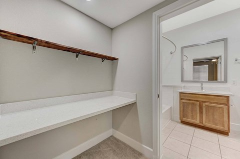 A white wall with a wooden shelf and a white sink cabinet.