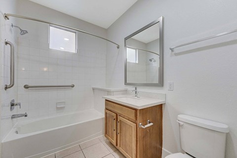 A white bathroom with a wooden cabinet and a white toilet.