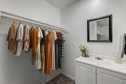 A row of clothes hanging on a rail in a white room.
