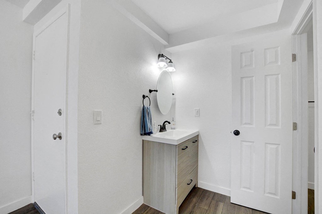 A white bathroom with a sink and a mirror.