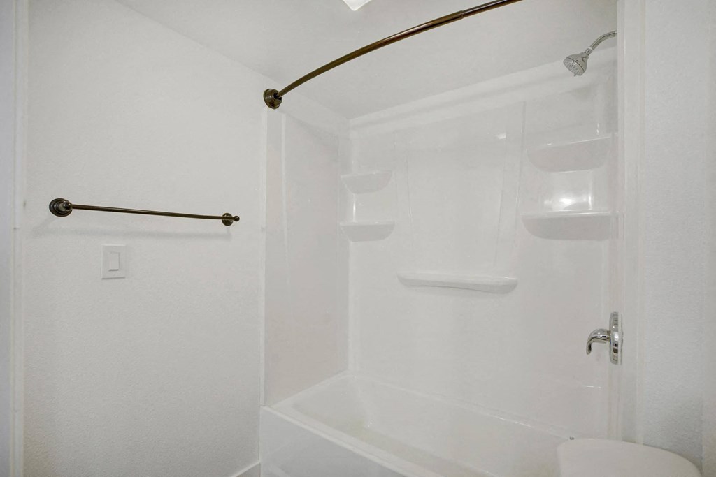 A white bathroom with a tub and toilet.