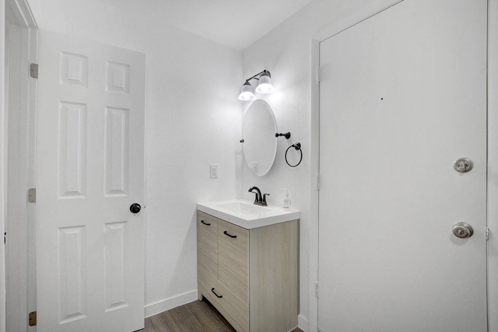 A white bathroom with a sink and a mirror.