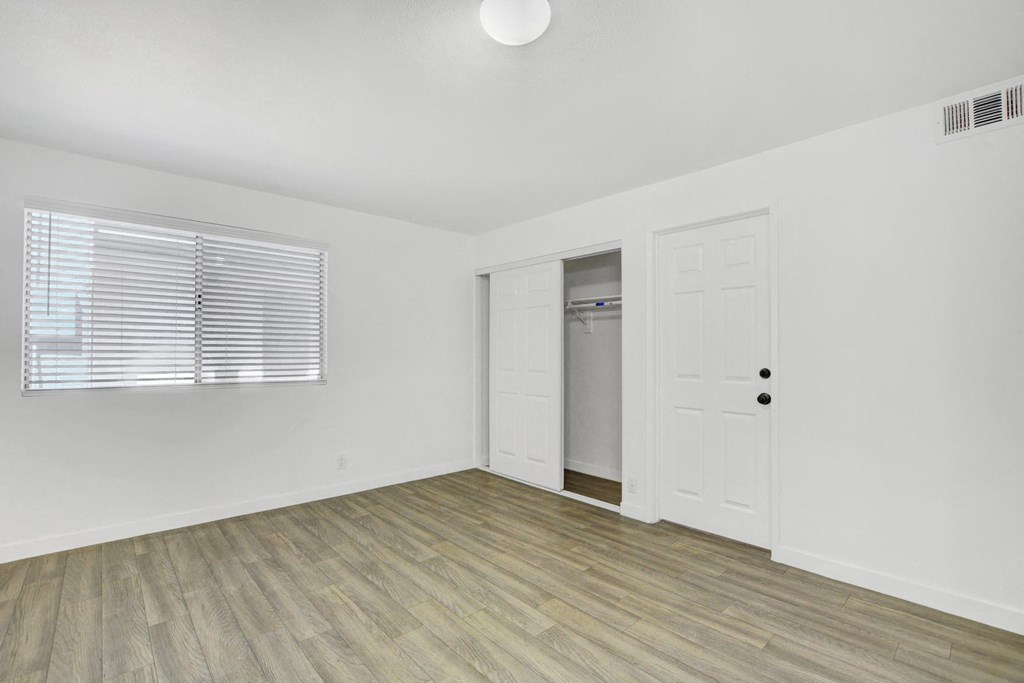 A room with a white door and a window with blinds.