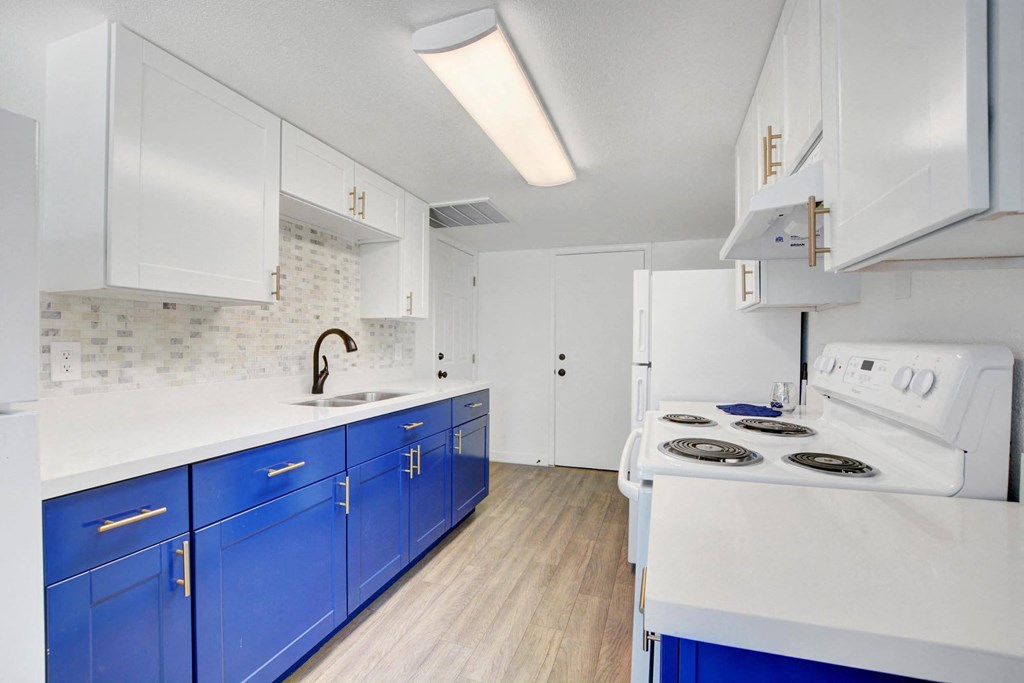 A kitchen with blue cabinets and a white stove top oven.