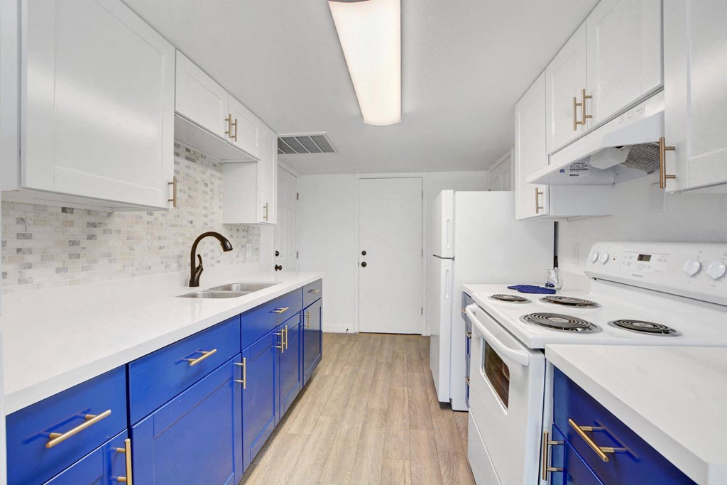 A kitchen with white and blue cabinets and appliances.