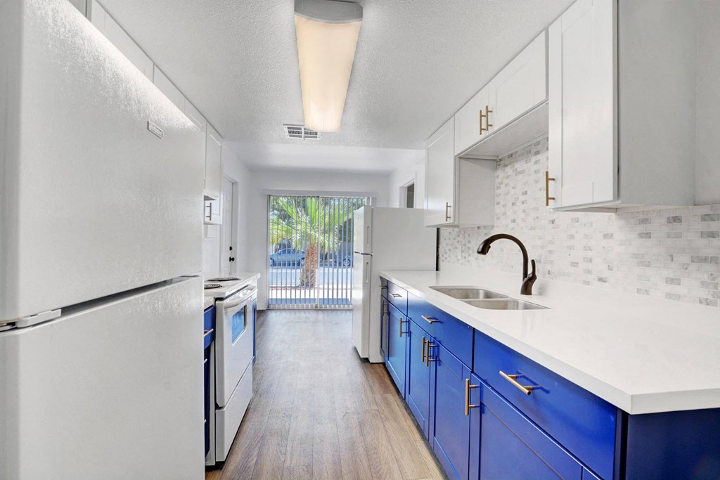 A kitchen with white appliances and blue cabinets.