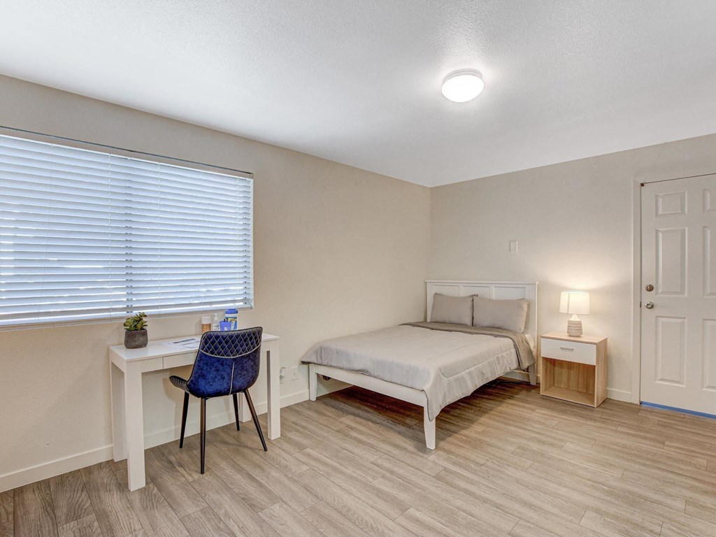 A bedroom with a bed, desk, and chair.