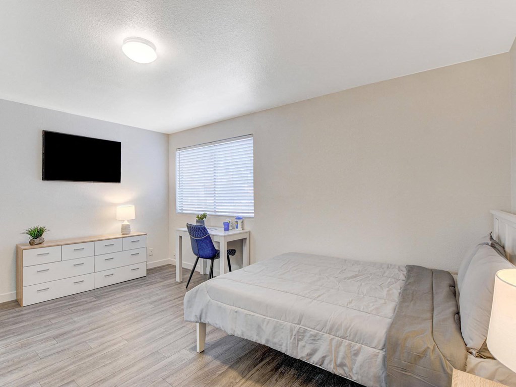 A bedroom with a bed, desk, and chair.