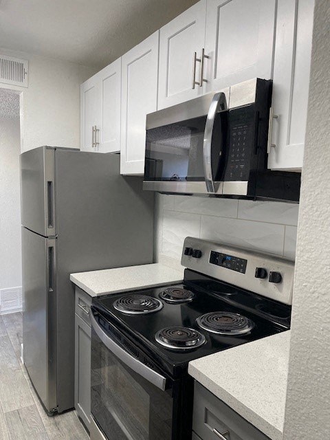A kitchen with a stove, refrigerator, and microwave.