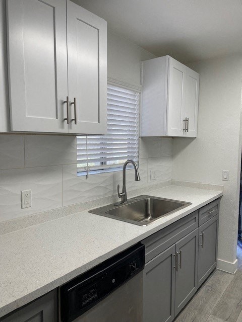 A kitchen with white cabinets and a black dishwasher.