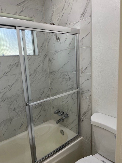 A white toilet sits next to a glass shower door.