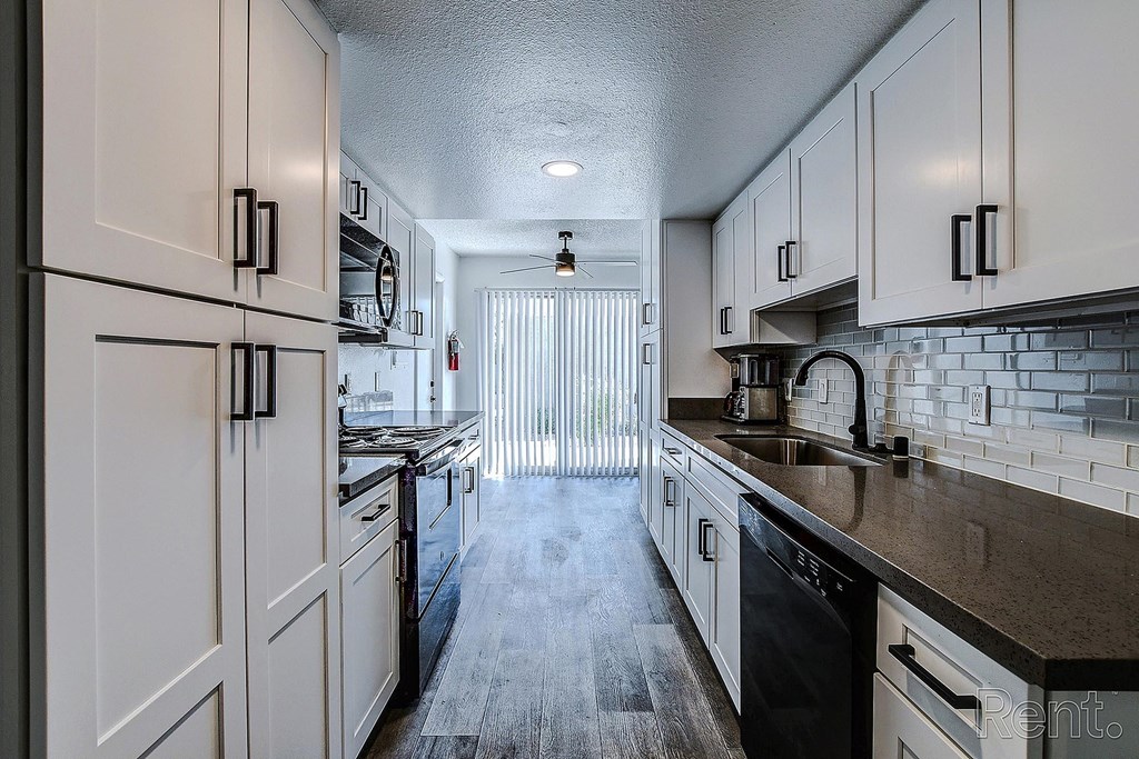 A kitchen with white cabinets and black appliances.