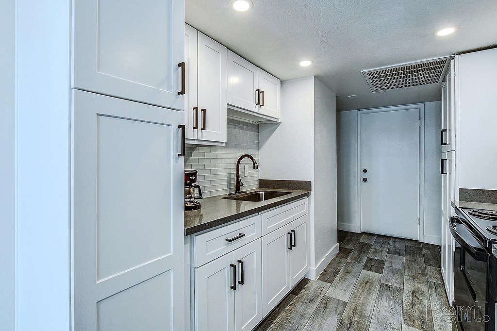 A kitchen with white cabinets and a wooden floor.