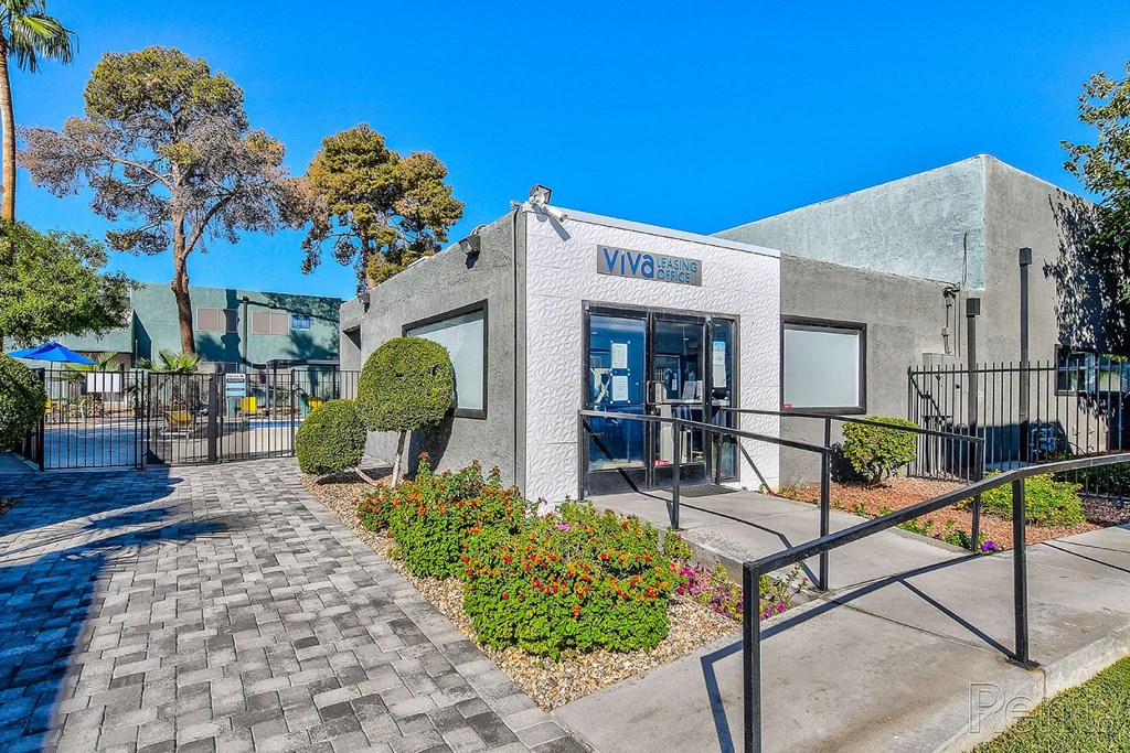 A building with the word "VIVA" on it is surrounded by a gate and has a walkway leading to the entrance.