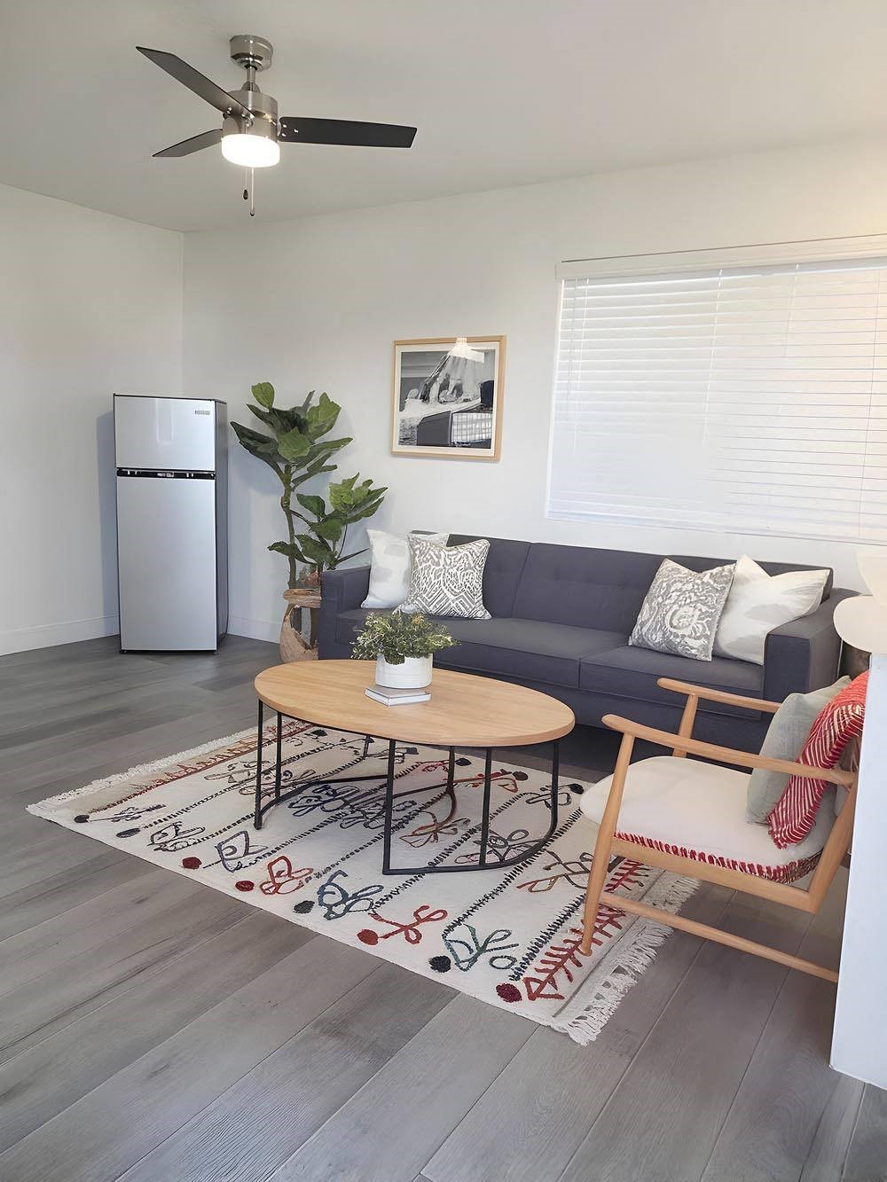 A living room with a grey couch, a wooden coffee table, and a ceiling fan.