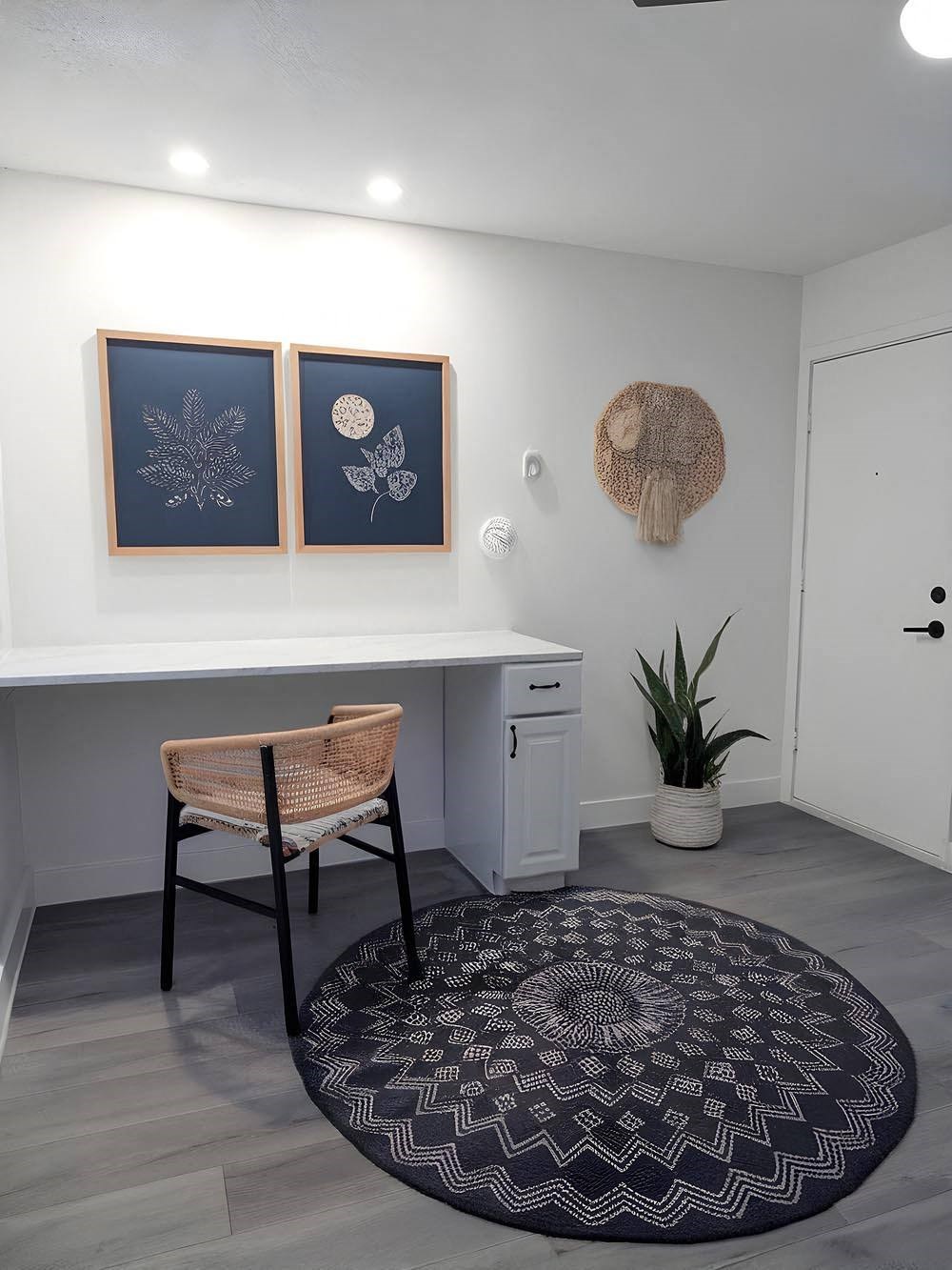A room with a desk, chair, and two framed pictures on the wall.